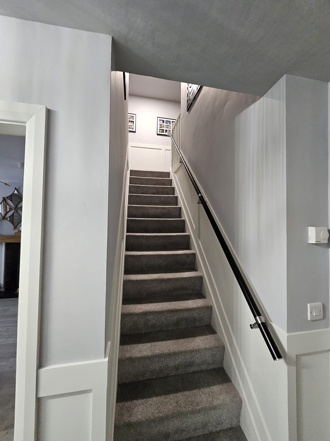 Black stainless steel wall mounted stair handrail with stainless steel brackets custom positioned to suit wall studs