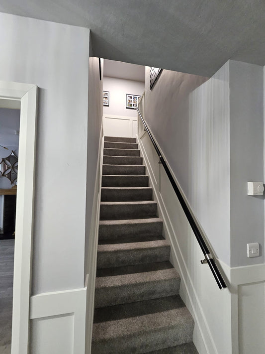 Black stainless steel wall mounted stair handrail with stainless steel brackets custom positioned to suit wall studs