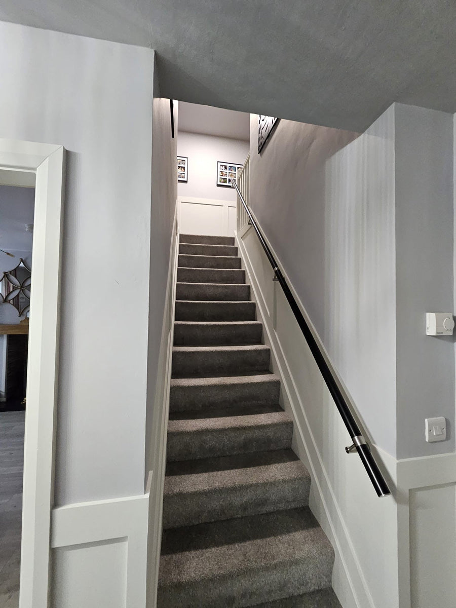 Black stainless steel wall mounted stair handrail with stainless steel brackets custom positioned to suit wall studs